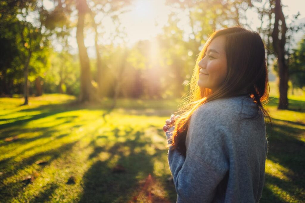 a person smiles in a sunlit forest after effectively managing withdrawal symptoms